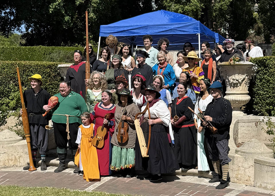 Photograph of cast and musicians in costume on an outdoor stage
