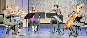 Photo of five musicians playing on stage in Lani Hall