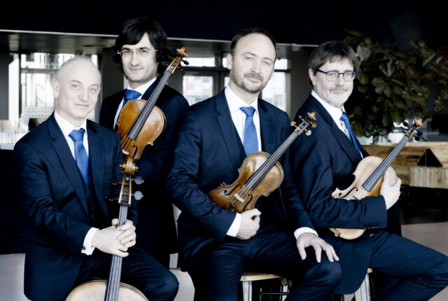 Four musicians in suits posing with their string instruments.